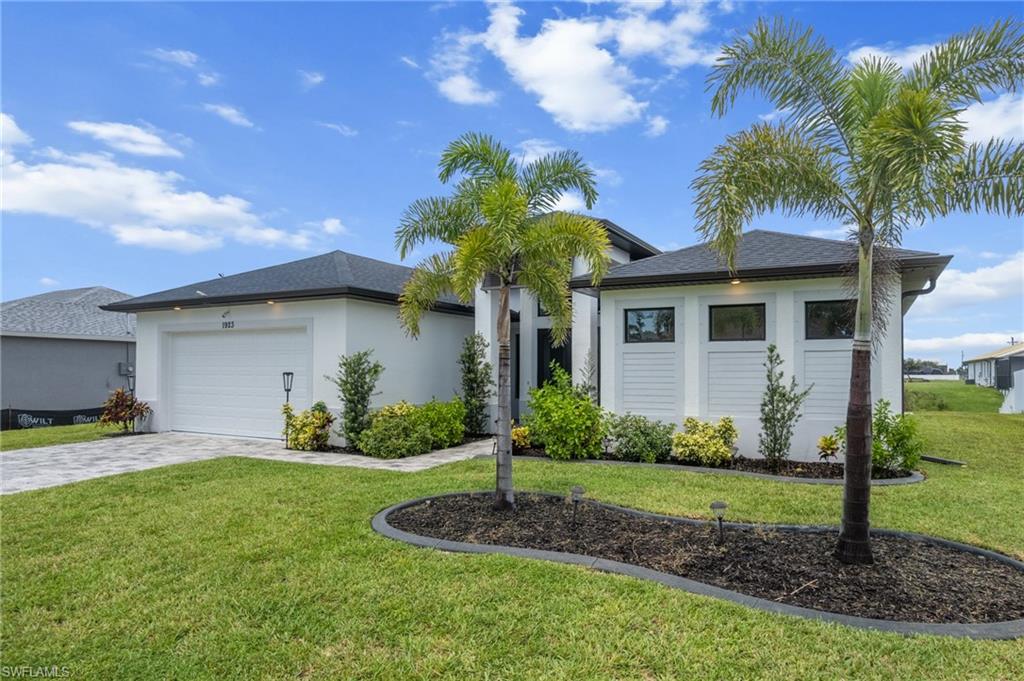 Ranch-style home with stucco siding, a front lawn, a garage, and decorative driveway