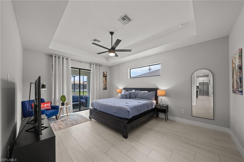 Bedroom featuring a raised ceiling, access to outside, ceiling fan, wood tiled floors, and arched walkways