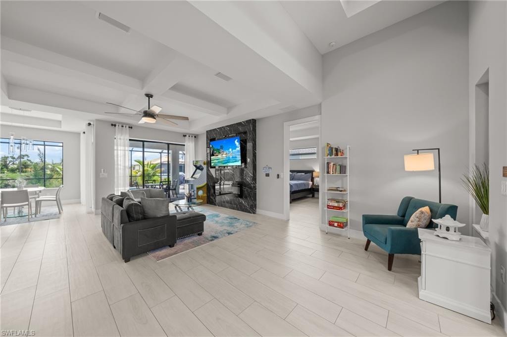 Living room with beamed ceiling, ceiling fan, coffered ceiling, and light wood finished floors