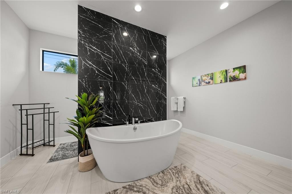 Bathroom featuring a freestanding bath, tile walls, and wood finish floors