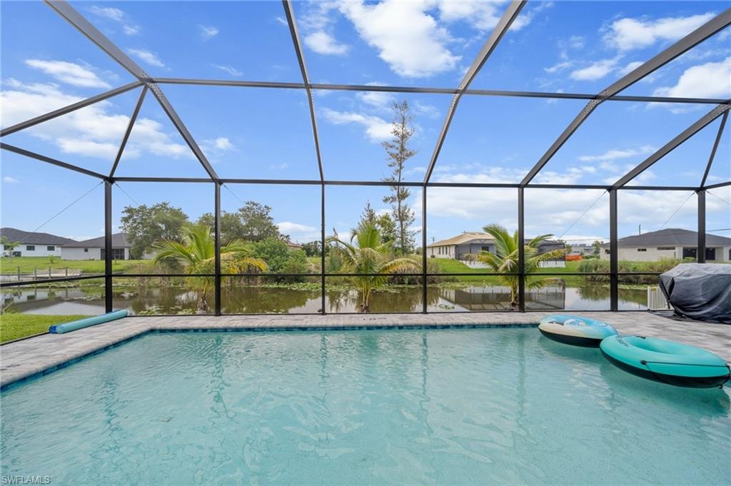 Swimming pool with a water view, a residential view, and glass enclosure