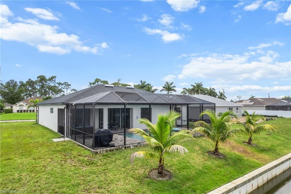 Back of property with a lawn and a lanai