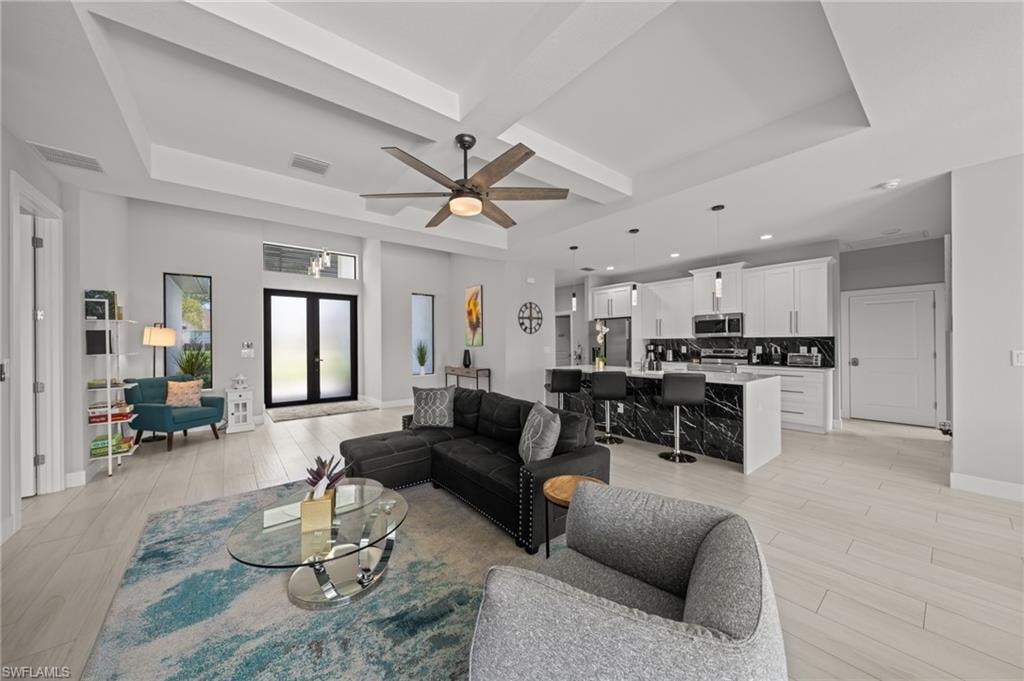 Living room featuring light wood-style floors, a ceiling fan, a raised ceiling, and recessed lighting
