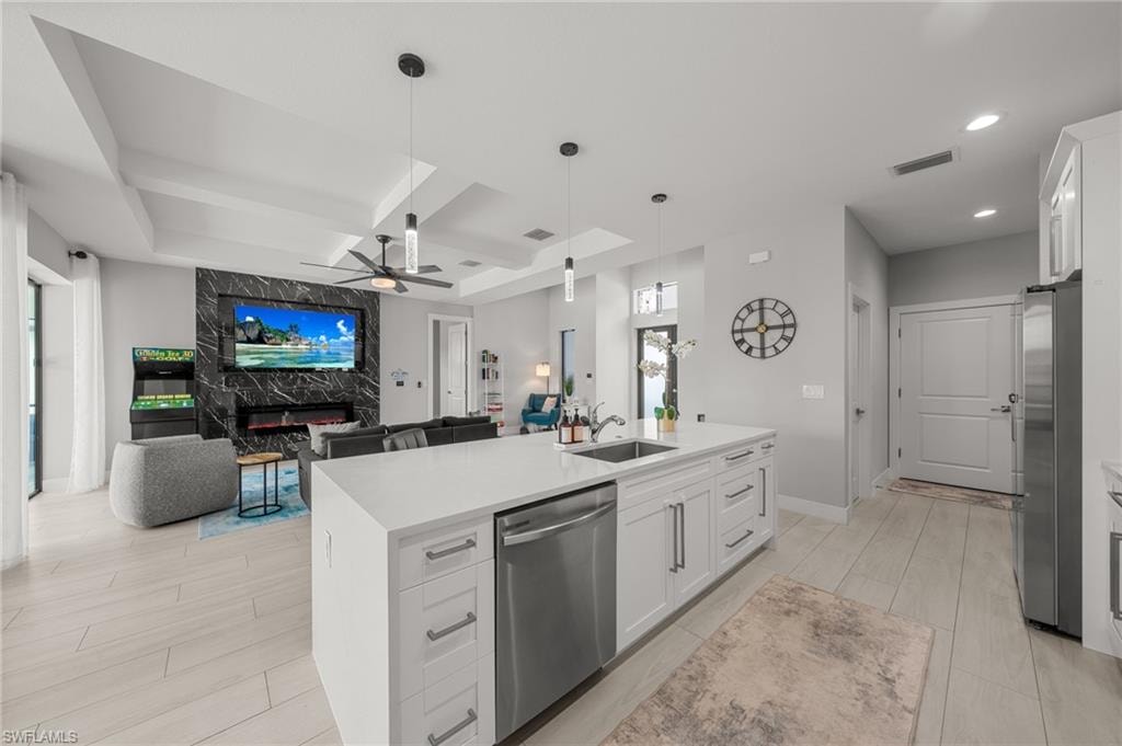 Kitchen featuring appliances with stainless steel finishes, ceiling fan, coffered ceiling, open floor plan, and wood tiled floors