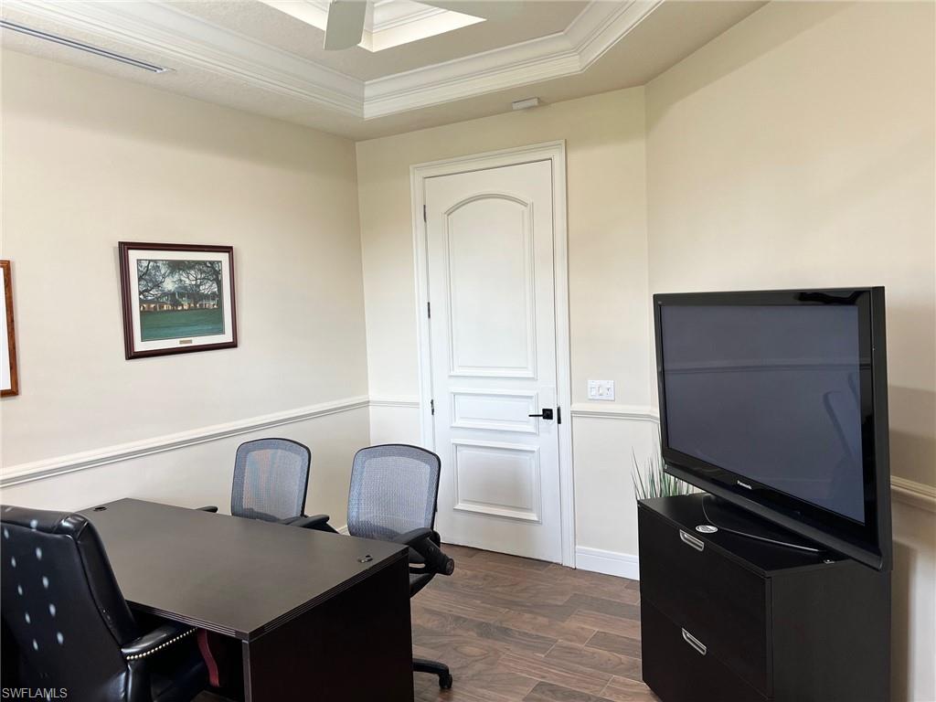 Office space featuring ornamental molding, a tray ceiling, a ceiling fan, and dark wood finished floors