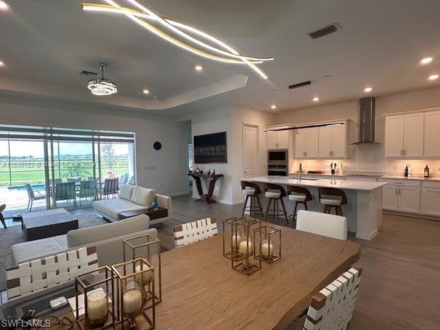 Dining space featuring sink, a tray ceiling, and wood-type flooring