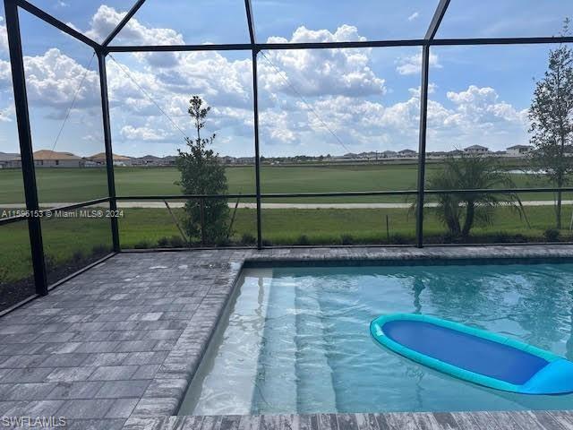 View of pool with glass enclosure and a patio area