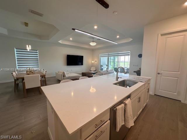Kitchen with white cabinets, sink, dishwashing machine, a kitchen island with sink, and dark hardwood / wood-style floors