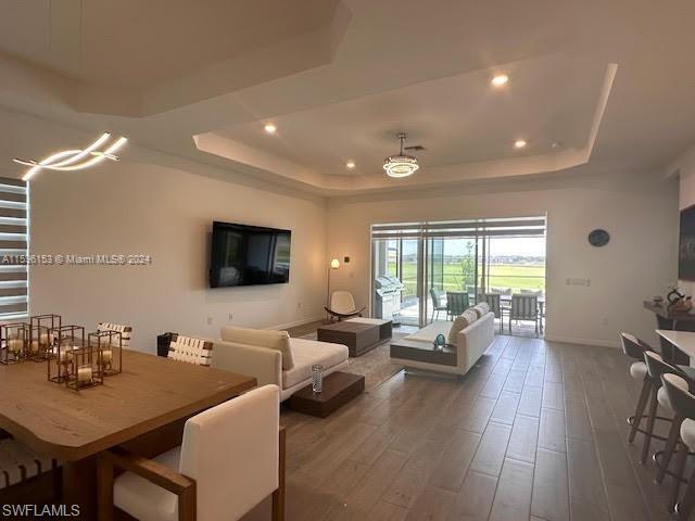 Living room featuring dark wood-type flooring and a tray ceiling