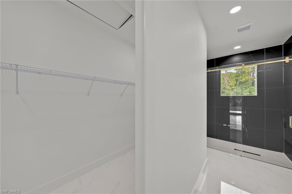 Walk in closet with marble tiled floors