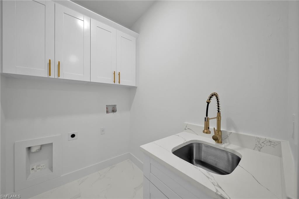 Laundry area with cabinet space, hookup for a washing machine, hookup for an electric dryer, and marble finish flooring