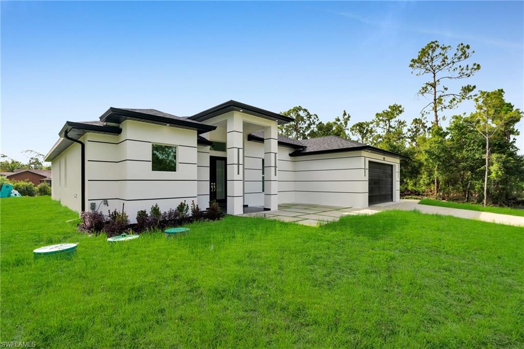 View of front of property featuring an attached garage, driveway, and a front lawn