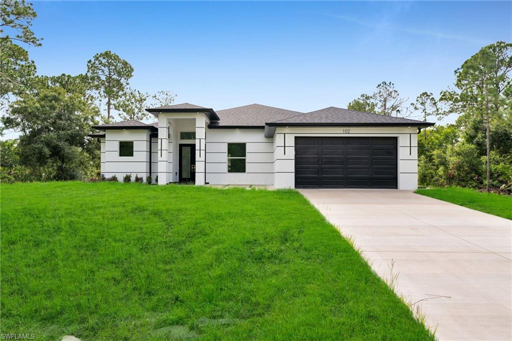 Prairie-style house featuring concrete driveway, an attached garage, a front lawn, and roof with shingles