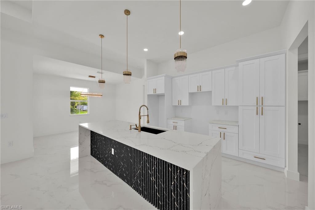 Kitchen featuring light marble finish flooring, white cabinetry, a kitchen island with sink, light stone countertops, and recessed lighting