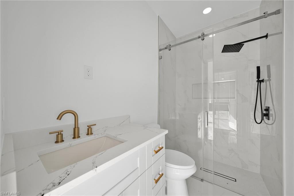 Full bathroom featuring a marble finish shower, vanity, and recessed lighting