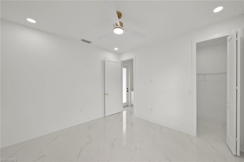Unfurnished bedroom with light marble finish flooring, recessed lighting, a spacious closet, and ceiling fan