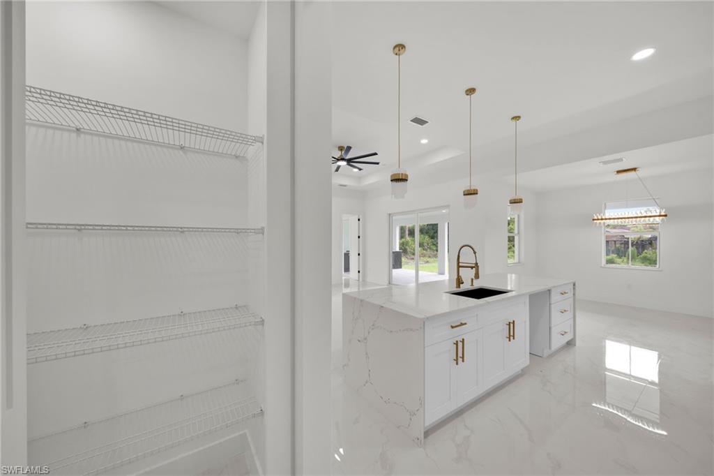Kitchen with light marble finish floors, light stone countertops, recessed lighting, white cabinets, and a ceiling fan