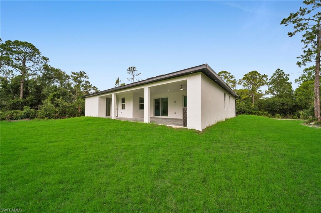 Back of property featuring stucco siding, a patio, and a lawn