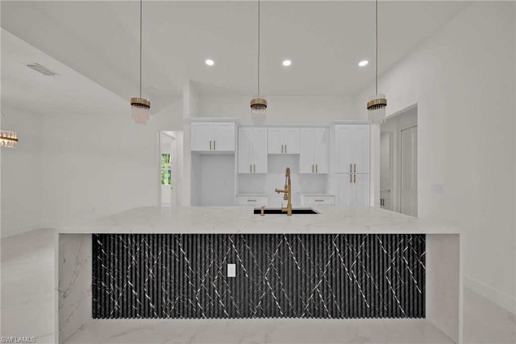 Kitchen with light marble finish flooring, recessed lighting, white cabinets, and light stone counters