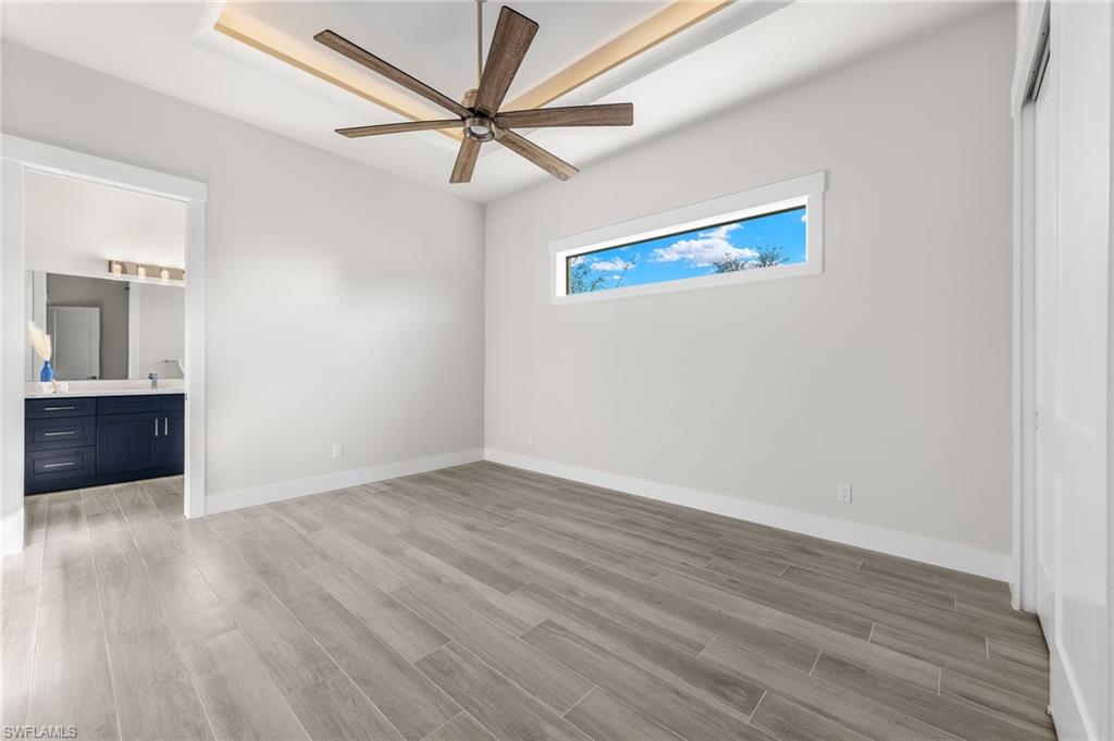 Guest bedroom 1 main floor featuring ensuite bath, ceiling fan, and light hardwood / wood-style floors