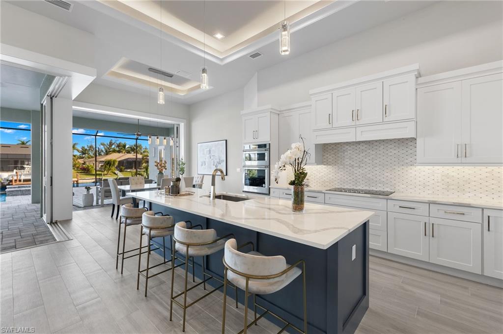 Kitchen featuring an island with sink, white cabinetry, and sink