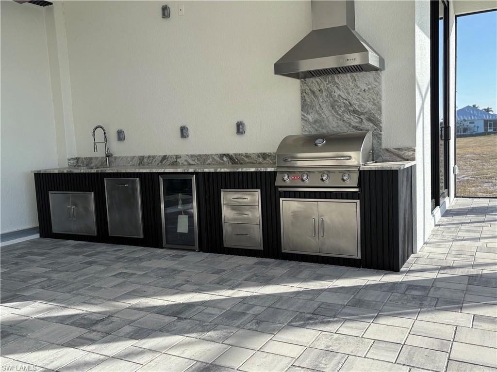 Kitchen featuring stainless steel fridge, wall chimney exhaust hood, and sink