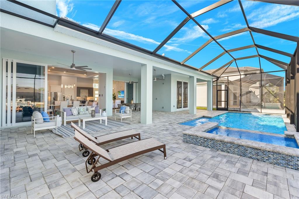 View of swimming pool featuring ceiling fan, an in ground hot tub, a patio, and glass enclosure