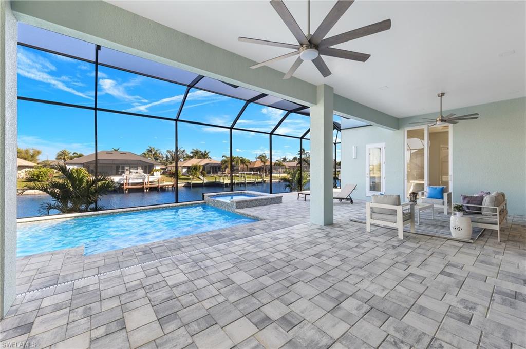 View of swimming pool featuring an in ground hot tub, a lanai, outdoor lounge area, a water view, and a patio area