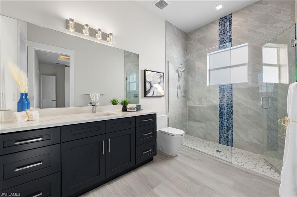Bathroom with vanity, toilet, and an enclosed shower