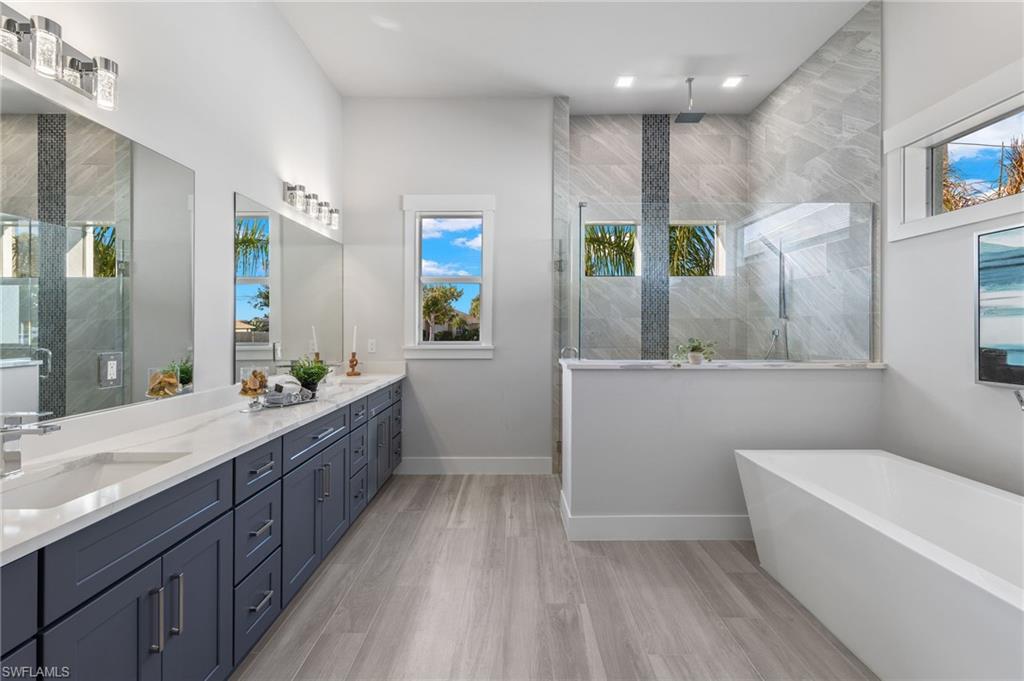 Bathroom featuring separate shower and tub, hardwood / wood-style floors, vanity, and a healthy amount of sunlight