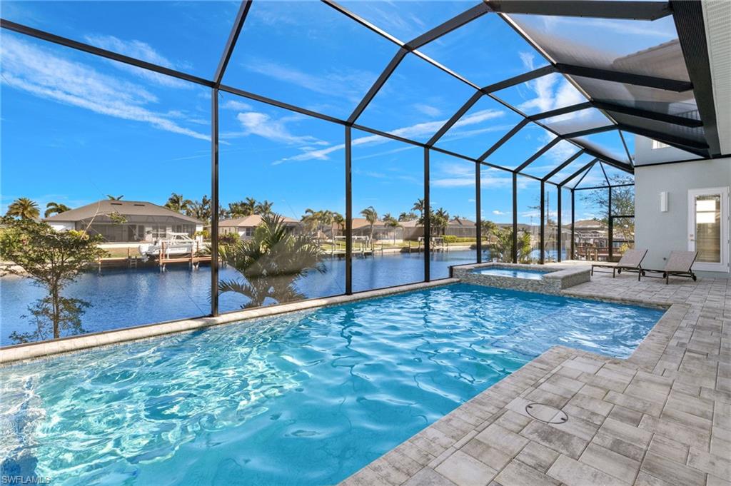 View of pool with a water view, a lanai, an in ground hot tub, and a patio