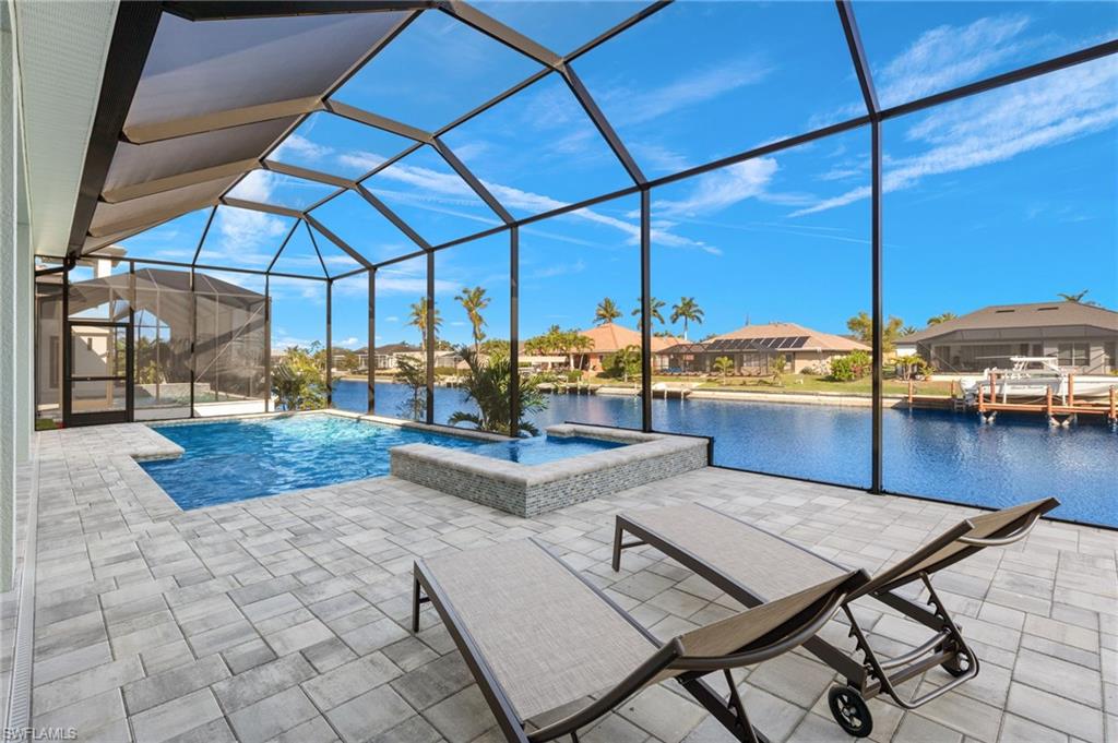View of swimming pool with a jacuzzi, a patio, a water view, and glass enclosure