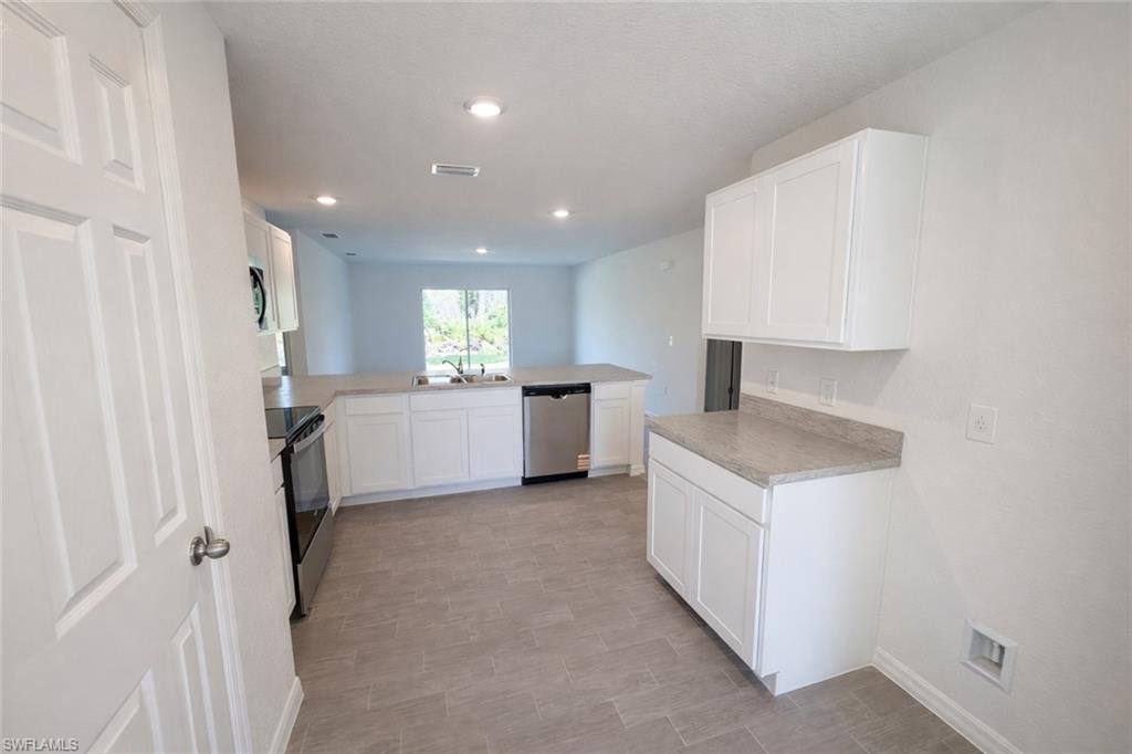 Kitchen featuring a peninsula, light countertops, and white cabinets