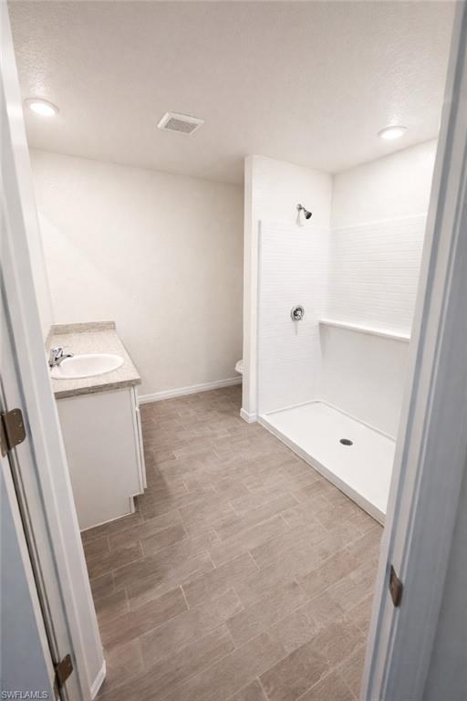 Bathroom featuring vanity, a shower stall, dark wood-style floors, and recessed lighting