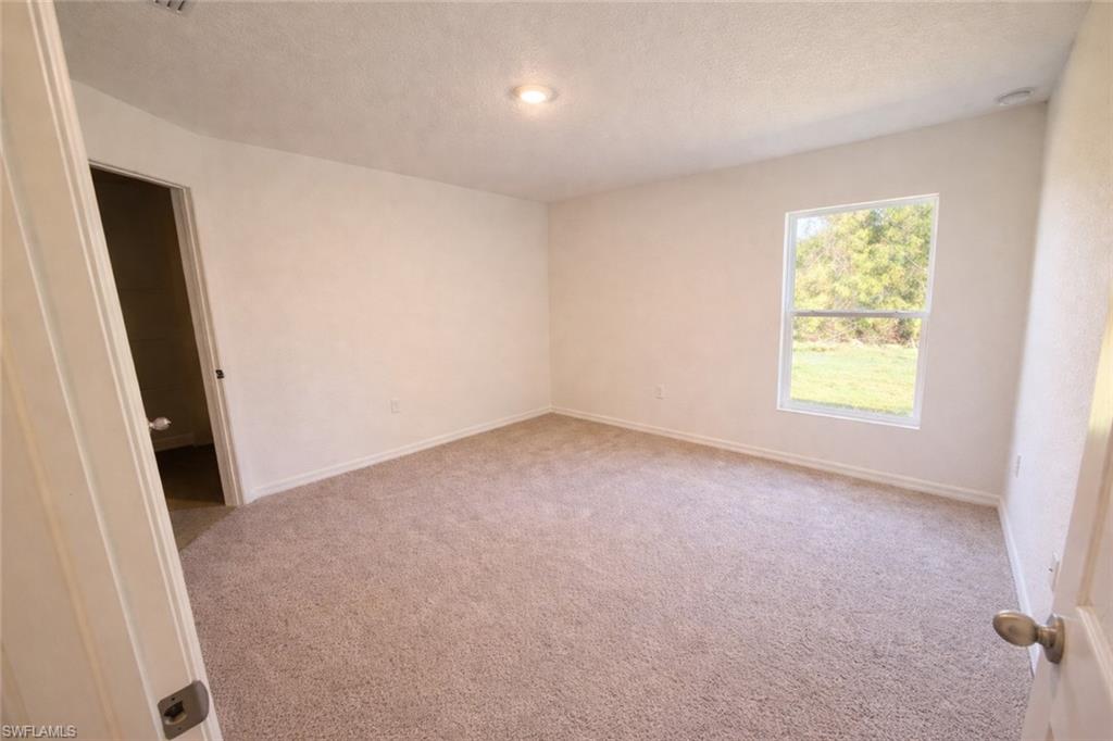 Unfurnished room featuring light carpet and a textured ceiling