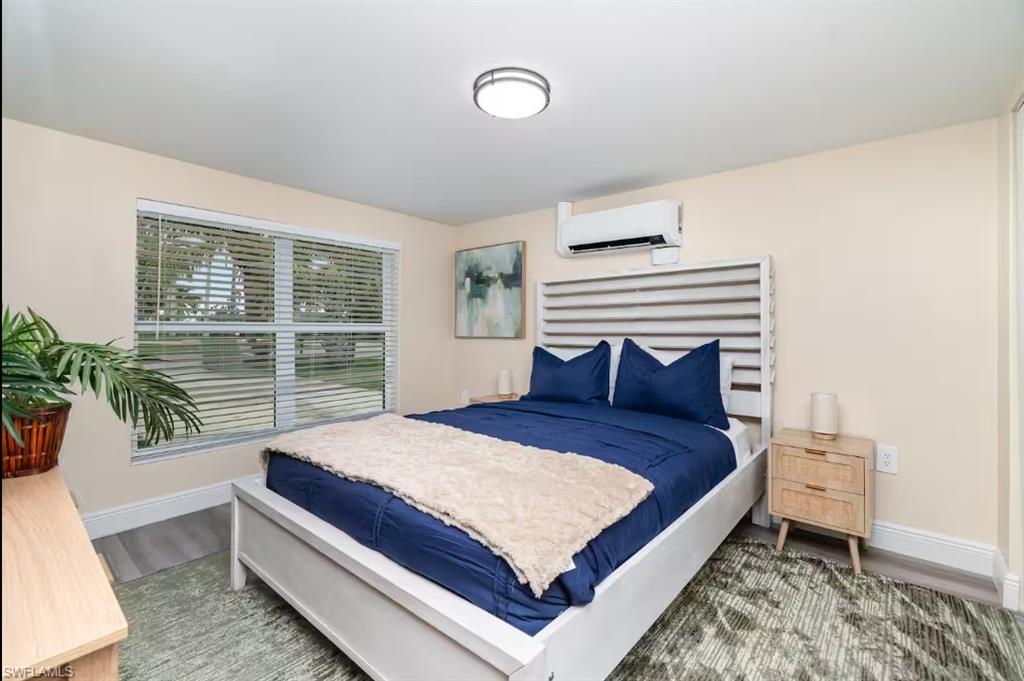 Bedroom featuring a wall mounted air conditioner and wood finished floors