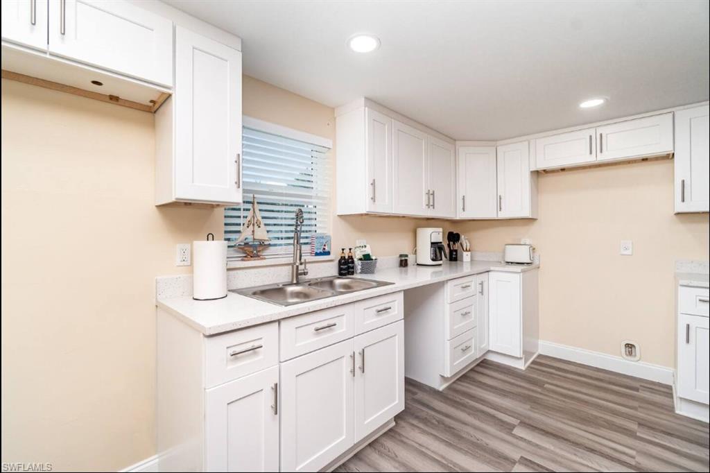 Kitchen with light wood finished floors, white cabinets, light countertops, and recessed lighting