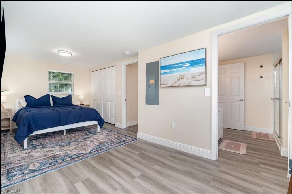 Bedroom with light wood-style flooring, electric panel, and a closet