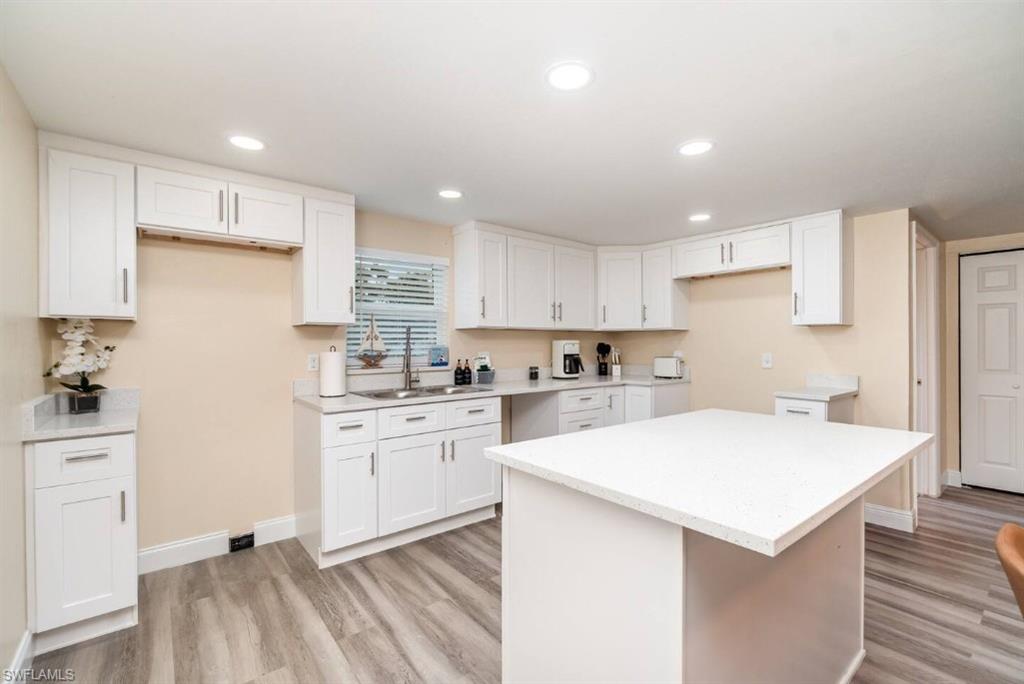 Kitchen featuring white cabinetry, a center island, light wood finished floors, recessed lighting, and light countertops