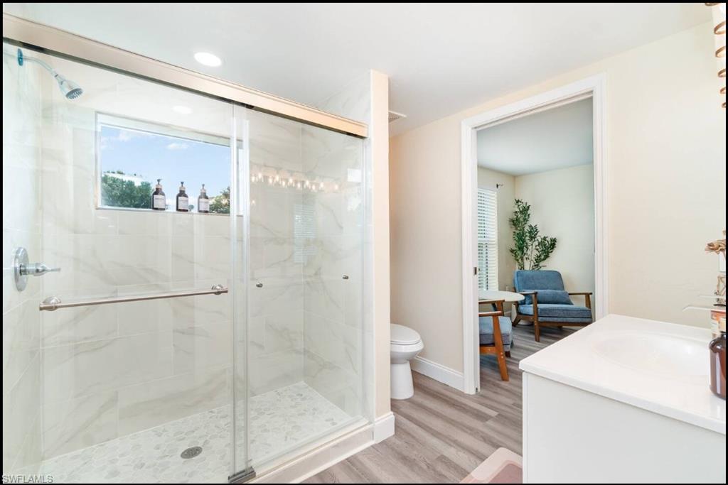 Full bath featuring a stall shower, wood finished floors, and vanity