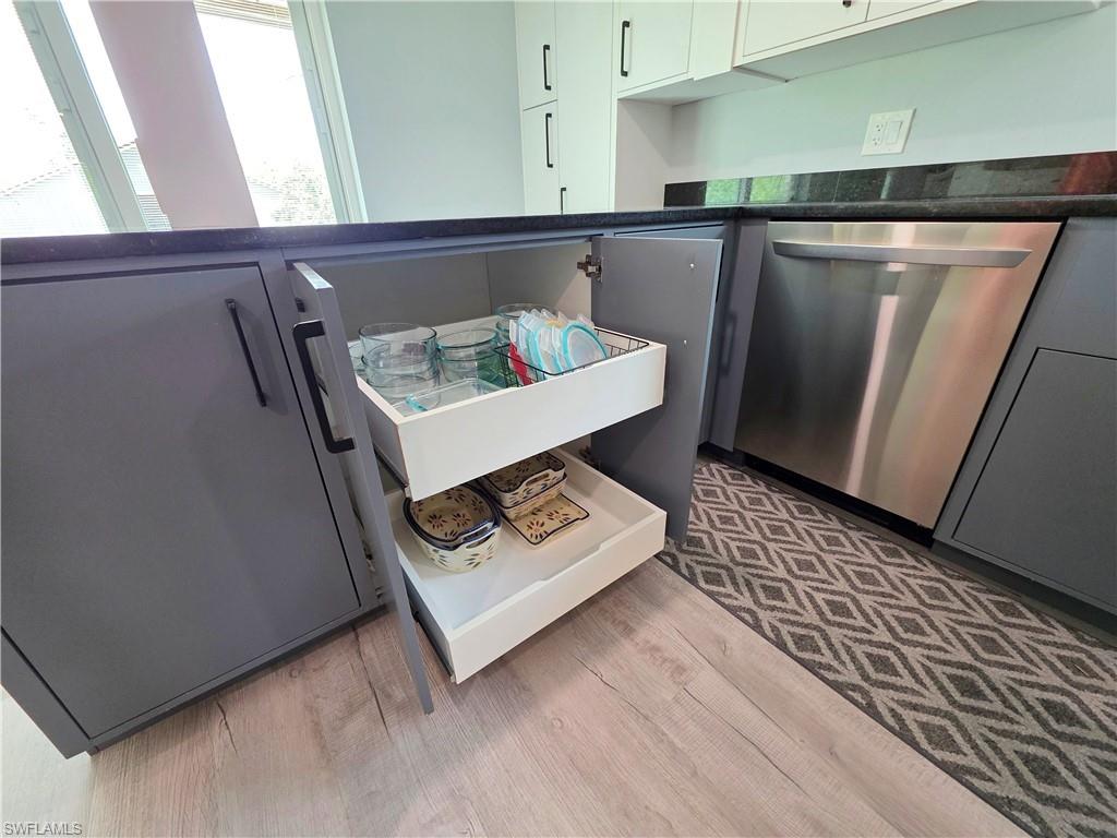 Kitchen with dishwasher, dark countertops, and light wood-style flooring