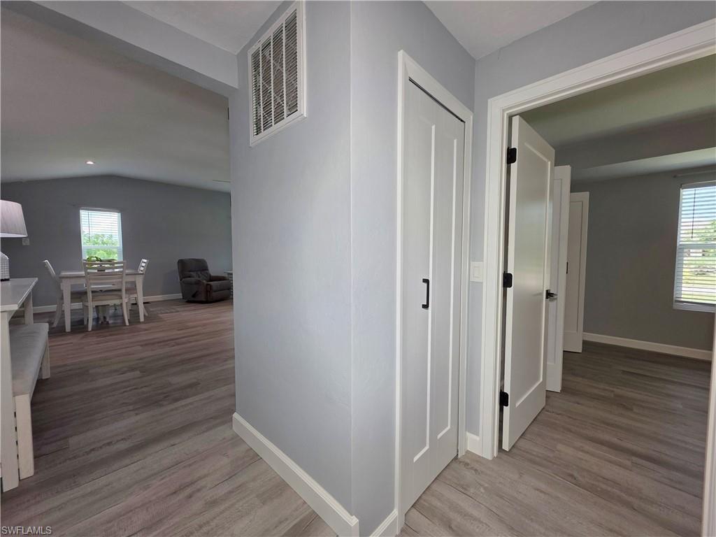 Hallway featuring plenty of natural light, wood finished floors, and vaulted ceiling