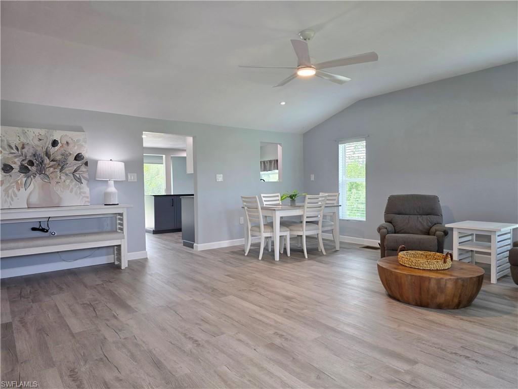 Dining space with healthy amount of natural light, wood finished floors, a ceiling fan, and lofted ceiling