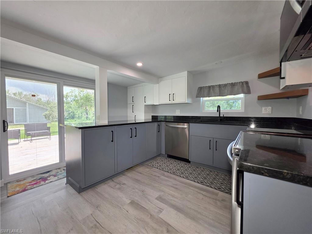 Kitchen featuring extractor fan, a peninsula, open shelves, electric range, and stainless steel dishwasher