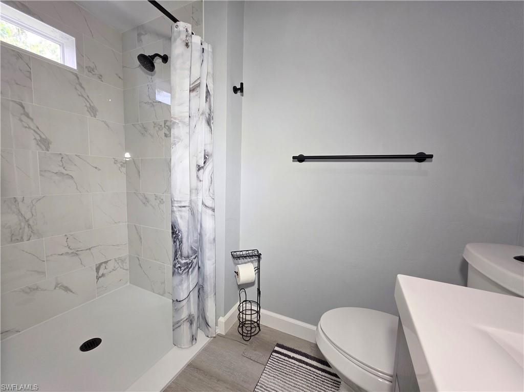 Full bathroom featuring wood finished floors, a tile shower, and vanity