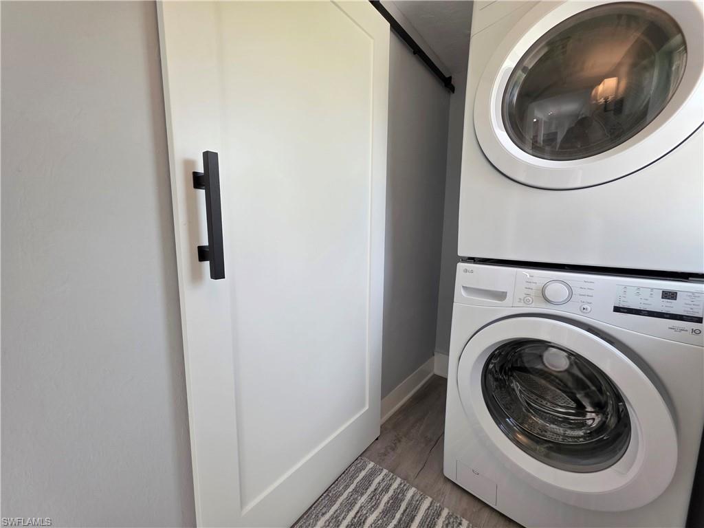 Washroom featuring stacked washer / drying machine and wood finished floors