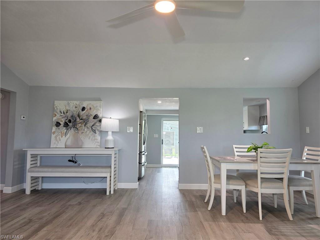 Dining space with lofted ceiling, wood finished floors, ceiling fan, and recessed lighting