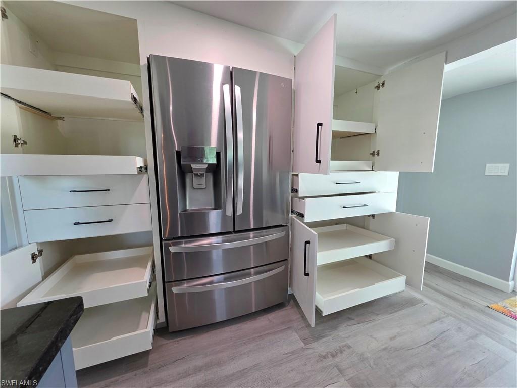 Kitchen featuring stainless steel fridge with ice dispenser and light wood finished floors