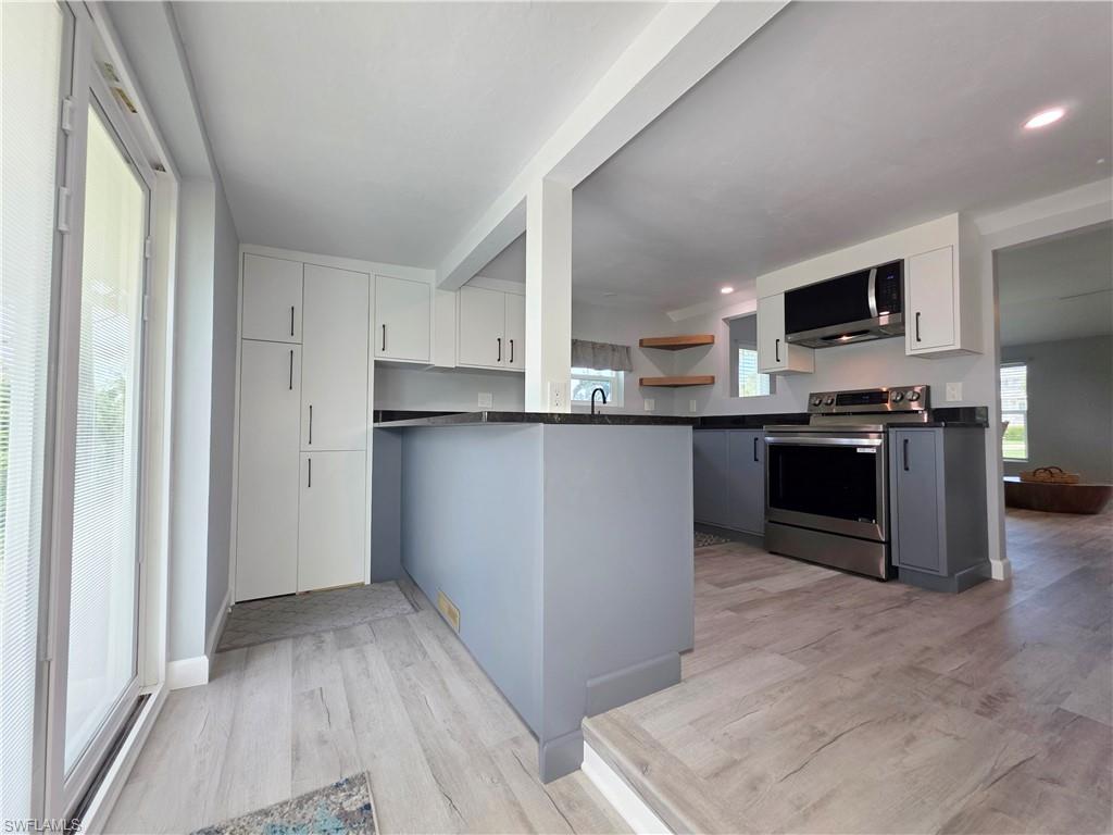 Kitchen featuring dark countertops, appliances with stainless steel finishes, light wood-type flooring, and a peninsula