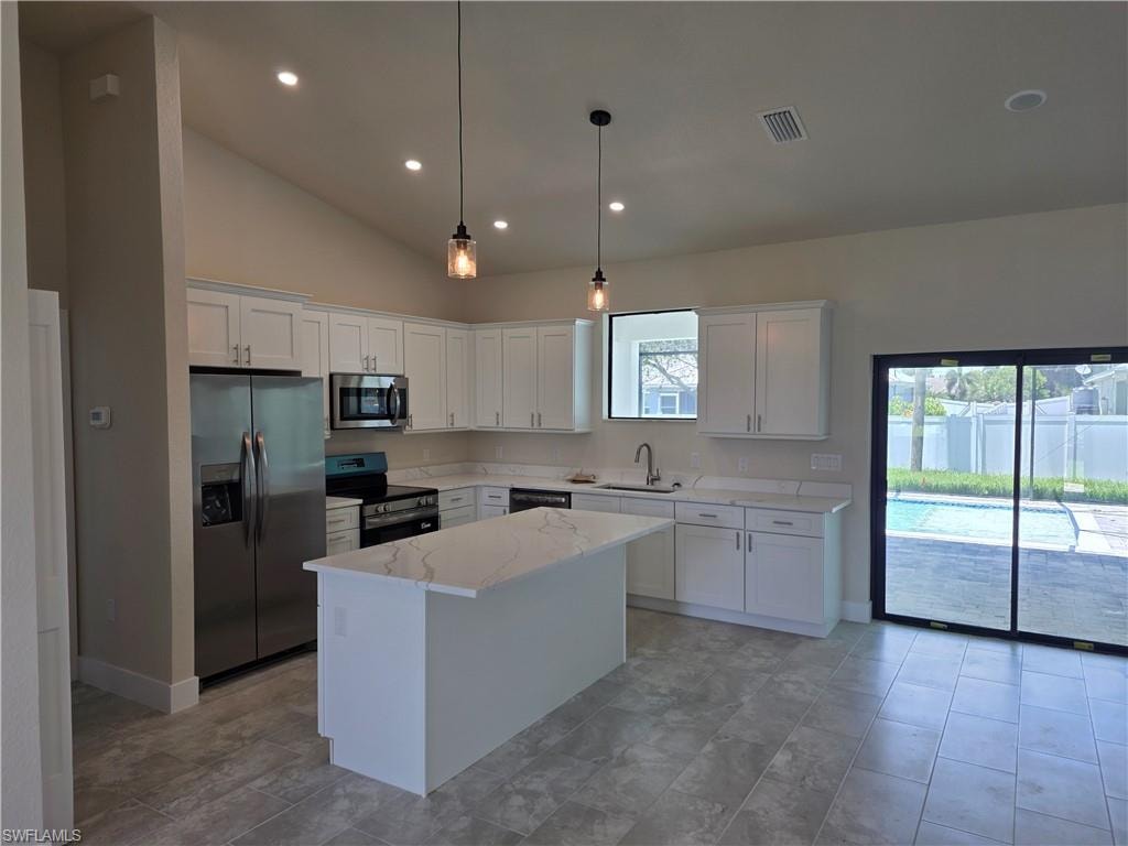 Modern kitchen featuring white cabinetry, stainless steel appliances, a center island with a quartz-like countertop, and tile flooring